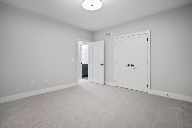 unfurnished bedroom featuring light colored carpet and a closet