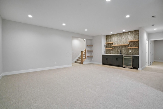 unfurnished living room featuring light carpet, wine cooler, and bar area