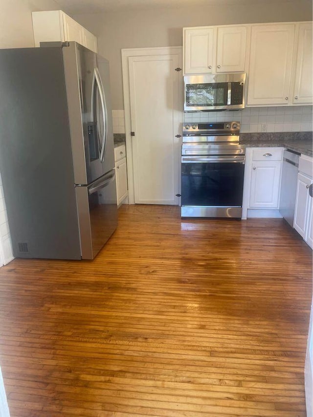 kitchen featuring tasteful backsplash, white cabinets, light hardwood / wood-style floors, and appliances with stainless steel finishes