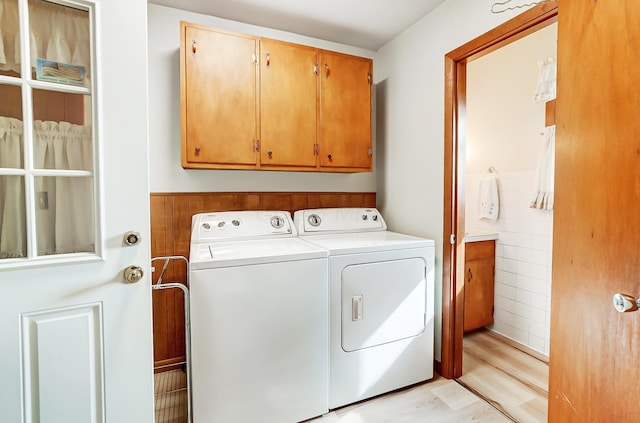 laundry room with cabinets, washing machine and clothes dryer, and light wood-type flooring