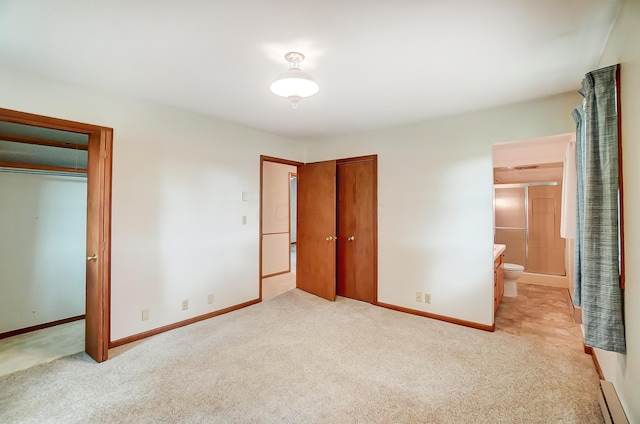 unfurnished bedroom featuring a baseboard heating unit, light carpet, ensuite bath, and a closet