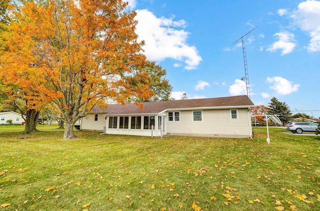 rear view of house featuring a yard and a sunroom