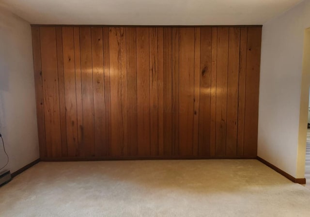 carpeted empty room with wood walls