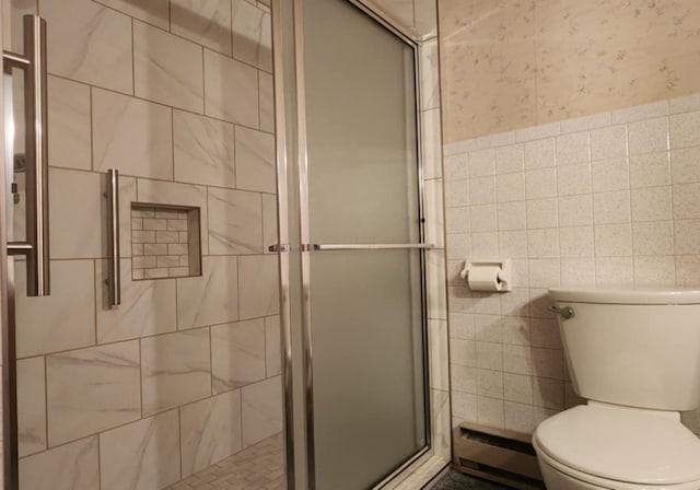 bathroom featuring toilet, a shower with door, tile walls, and a baseboard heating unit