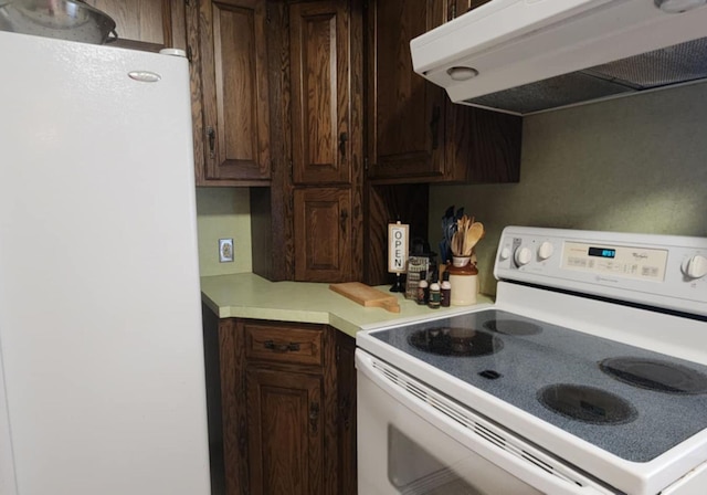 kitchen with extractor fan, white appliances, and dark brown cabinets