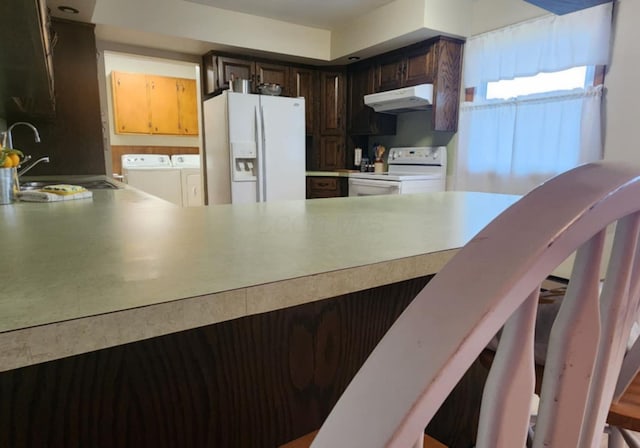 kitchen featuring sink, white appliances, dark brown cabinets, independent washer and dryer, and kitchen peninsula