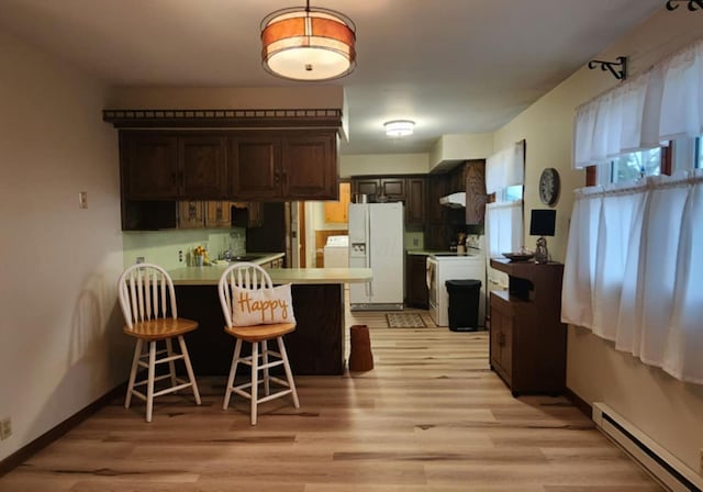 kitchen featuring a baseboard radiator, a kitchen bar, white fridge with ice dispenser, kitchen peninsula, and dark brown cabinets