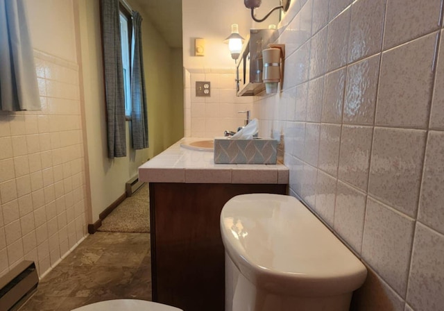 bathroom featuring baseboard heating, vanity, toilet, and tile walls