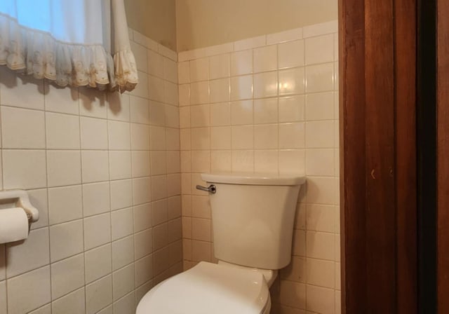 bathroom with toilet and tile walls