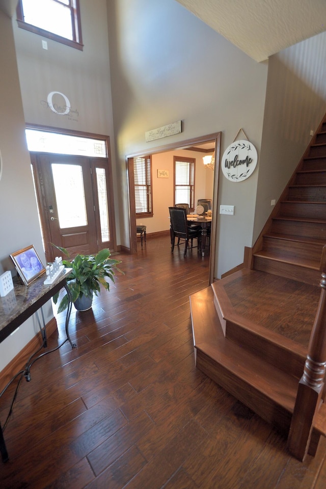 foyer entrance featuring dark hardwood / wood-style floors and a towering ceiling