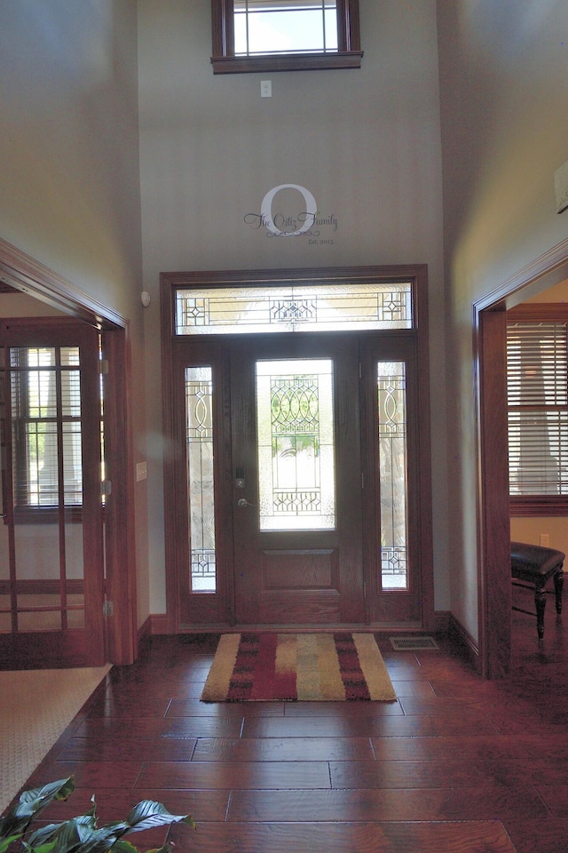 entryway featuring a towering ceiling and dark hardwood / wood-style flooring