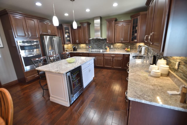 kitchen featuring dark wood-type flooring, sink, wall chimney range hood, a center island, and wine cooler