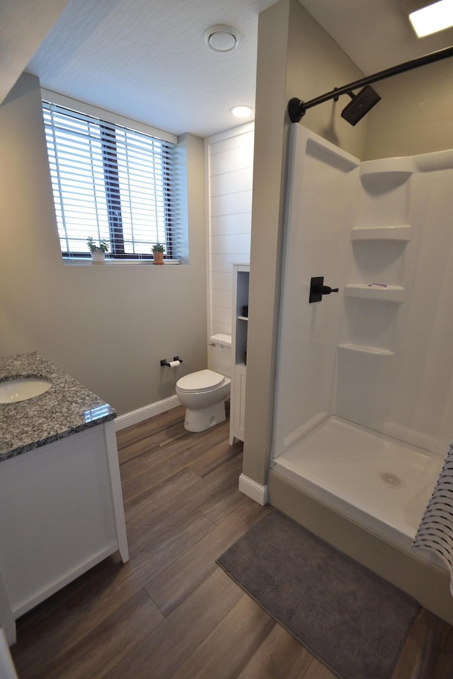 bathroom featuring a shower, hardwood / wood-style floors, vanity, and toilet