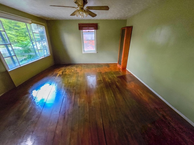 unfurnished room featuring ceiling fan, dark hardwood / wood-style flooring, and a textured ceiling