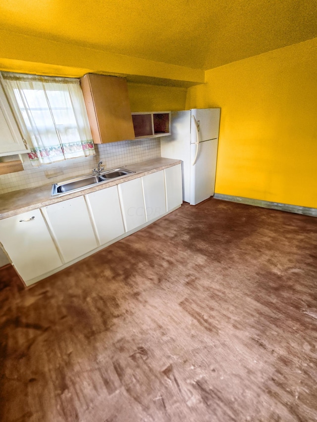 kitchen with white cabinets, white refrigerator, sink, and backsplash