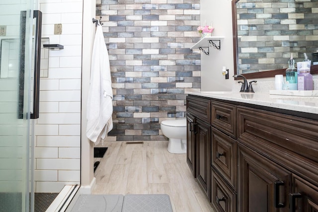 bathroom featuring walk in shower, vanity, hardwood / wood-style flooring, tile walls, and toilet