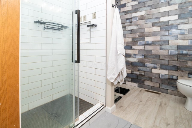 bathroom with hardwood / wood-style floors, an enclosed shower, and toilet