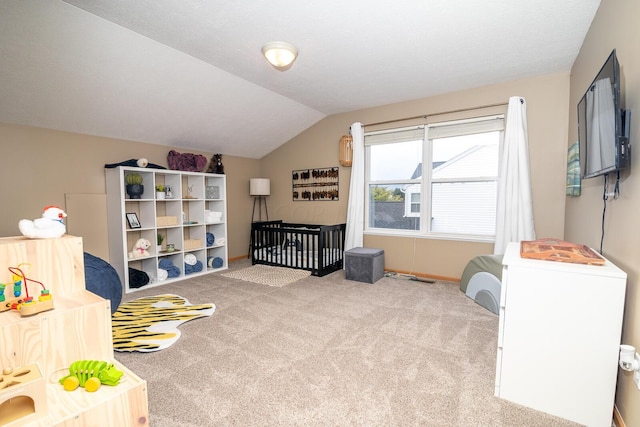 bedroom with light colored carpet, lofted ceiling, and a nursery area