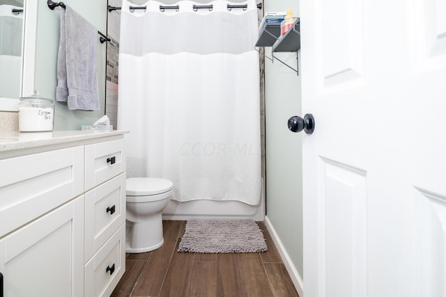 full bathroom featuring toilet, hardwood / wood-style floors, vanity, and shower / tub combo with curtain