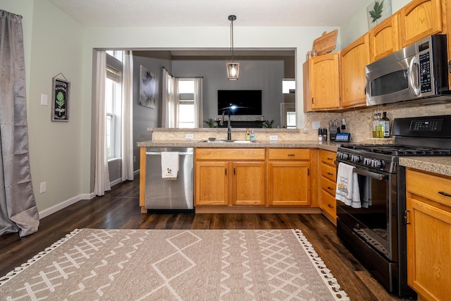 kitchen with appliances with stainless steel finishes, backsplash, dark wood-type flooring, sink, and pendant lighting