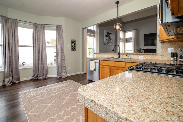 kitchen with dark wood-type flooring, sink, tasteful backsplash, decorative light fixtures, and stainless steel appliances