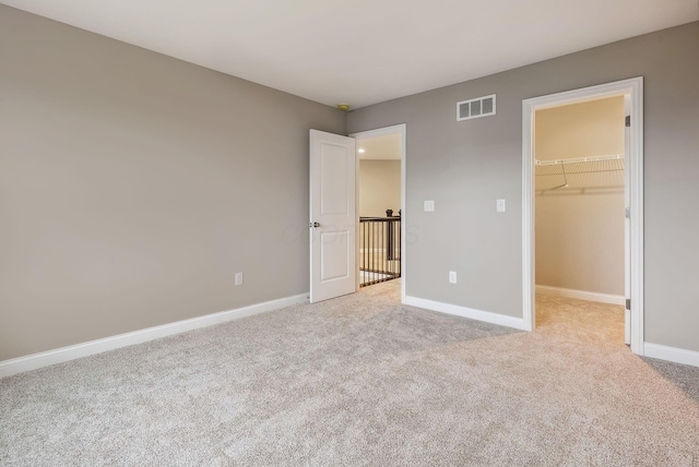 unfurnished bedroom with light carpet, a walk in closet, and a closet