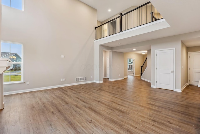 unfurnished living room featuring wood-type flooring and a high ceiling