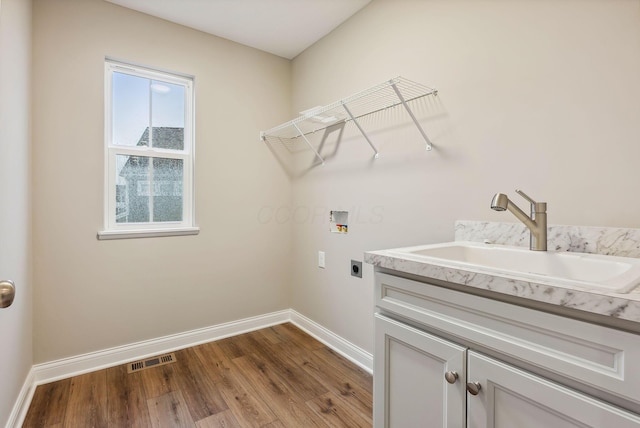 laundry area with electric dryer hookup, cabinets, sink, hookup for a washing machine, and light hardwood / wood-style flooring