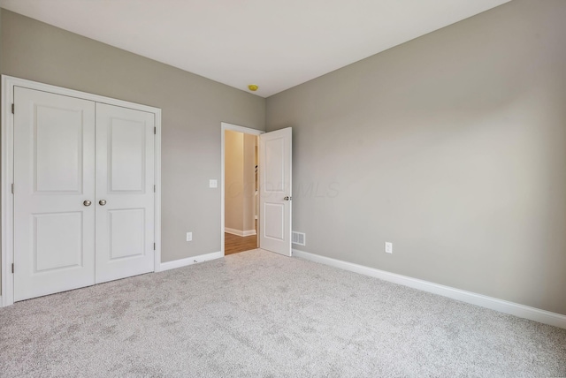 unfurnished bedroom featuring light colored carpet and a closet