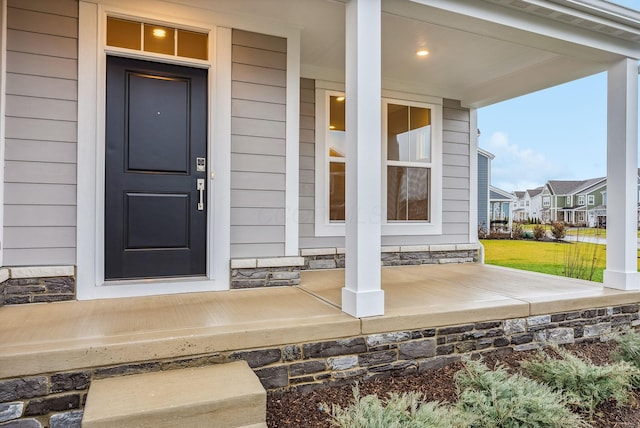 doorway to property featuring covered porch and a yard