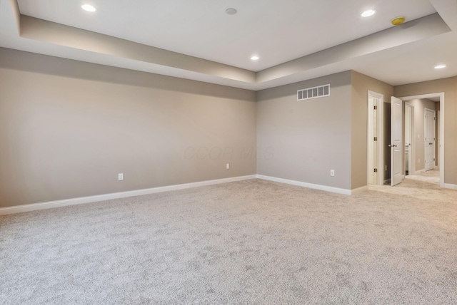 unfurnished room featuring a tray ceiling and light carpet