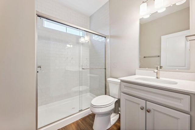 bathroom featuring wood-type flooring, vanity, toilet, and walk in shower