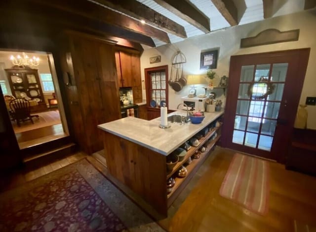 bar featuring a chandelier, beam ceiling, sink, and hardwood / wood-style floors