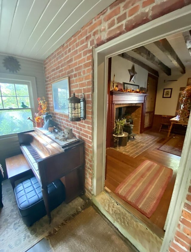 interior space featuring hardwood / wood-style flooring, beam ceiling, and brick wall