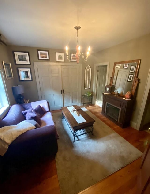 living room with a chandelier, wood-type flooring, and a fireplace