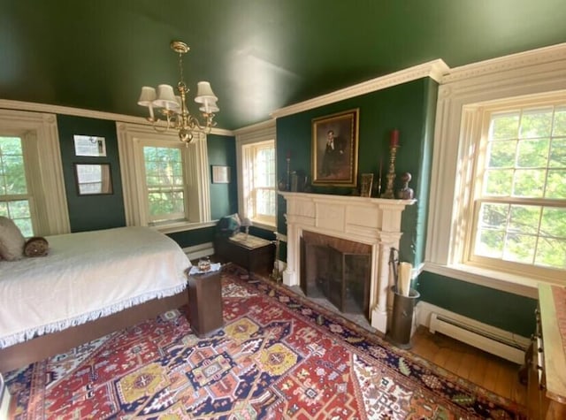 bedroom with multiple windows, hardwood / wood-style floors, baseboard heating, and a notable chandelier