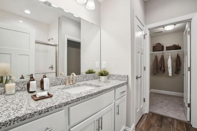 bathroom with hardwood / wood-style floors, vanity, and a shower with door