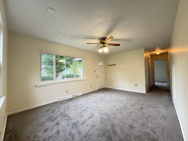 carpeted spare room featuring ceiling fan and a textured ceiling