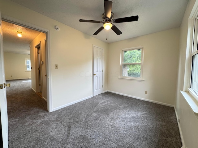 unfurnished bedroom featuring a textured ceiling, dark carpet, and ceiling fan