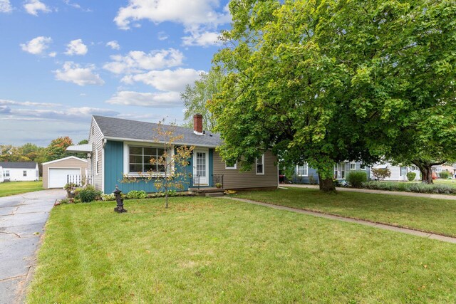 view of front of house featuring a garage, an outdoor structure, and a front yard