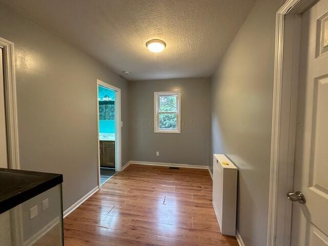 spare room with a textured ceiling, light wood-type flooring, and radiator heating unit