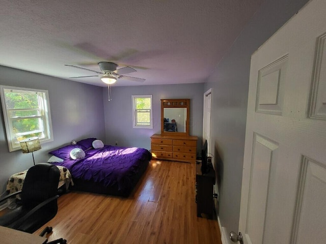 bedroom with multiple windows, ceiling fan, hardwood / wood-style floors, and a textured ceiling