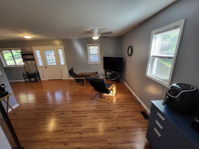 living room featuring a wealth of natural light, dark wood-type flooring, and ceiling fan