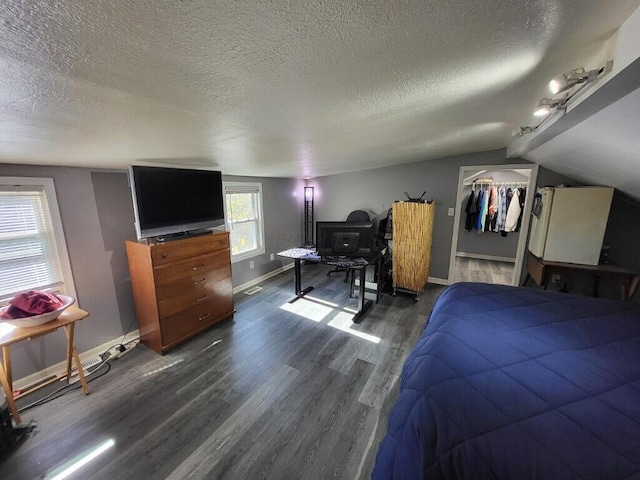 bedroom featuring a textured ceiling, dark hardwood / wood-style floors, a closet, and lofted ceiling