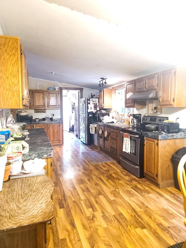 kitchen with range with electric cooktop, sink, stainless steel fridge, vaulted ceiling, and light wood-type flooring