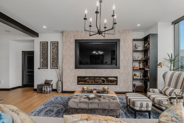 living room with a large fireplace, wood-type flooring, and an inviting chandelier