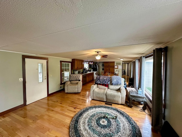 living room featuring a textured ceiling, light wood-type flooring, and ceiling fan