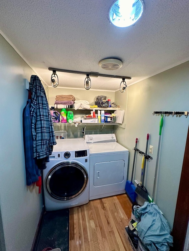 washroom featuring a textured ceiling, light wood-type flooring, and washer and clothes dryer