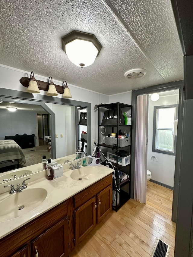 bathroom with hardwood / wood-style floors, vanity, toilet, and a textured ceiling