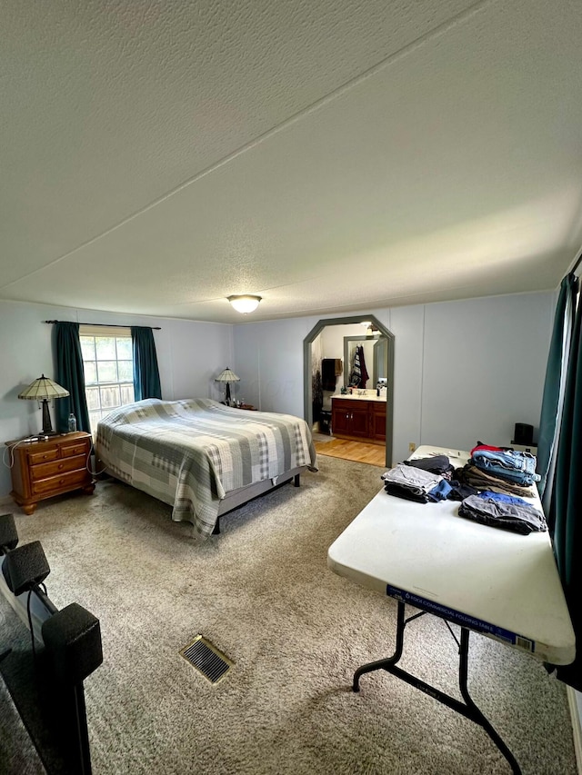 bedroom featuring carpet, a textured ceiling, and ensuite bath